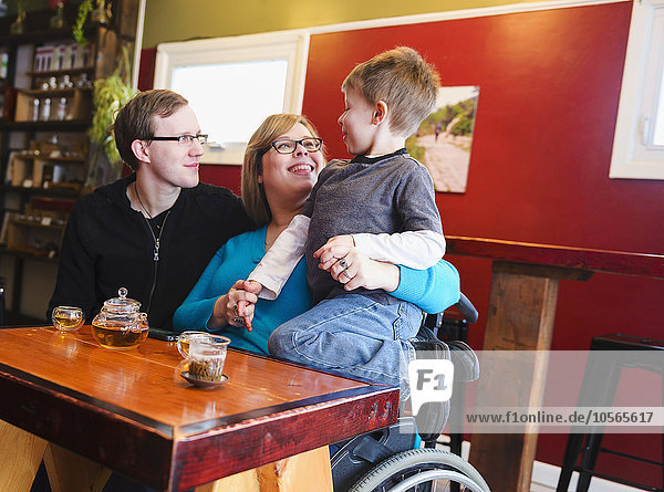 Querschnittsgelähmte Mutter hält ihren Sohn im Teeladen