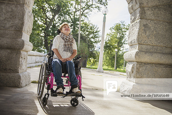 Querschnittsgelähmte Frau im Rollstuhl unter Steinbogen