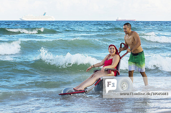 Behindertensport Mann Freundin schieben Strand Rollstuhl