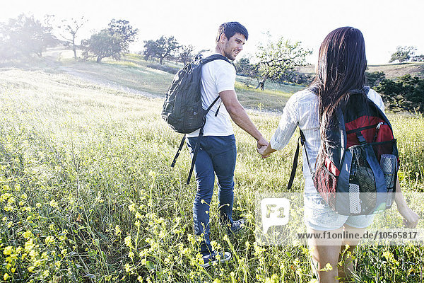 Couple carrying backpacks in field
