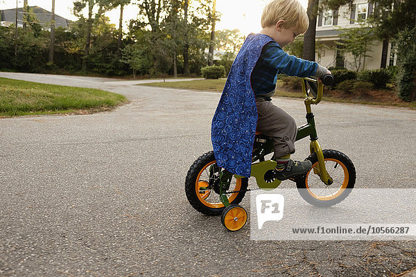 Caucasian boy riding bicycle with training wheels