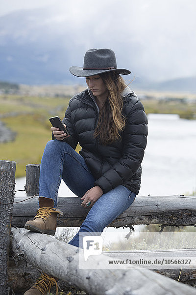Kaukasische Frau benutzt Handy an einem ländlichen Fluss
