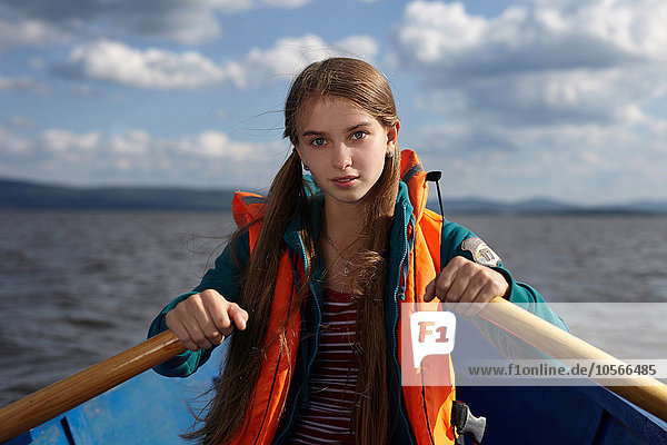 Kaukasisches Mädchen rudert Kanu auf einem See