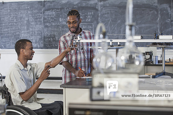 Querschnittsgelähmter Schüler arbeitet mit einem Klassenkameraden im naturwissenschaftlichen Unterricht