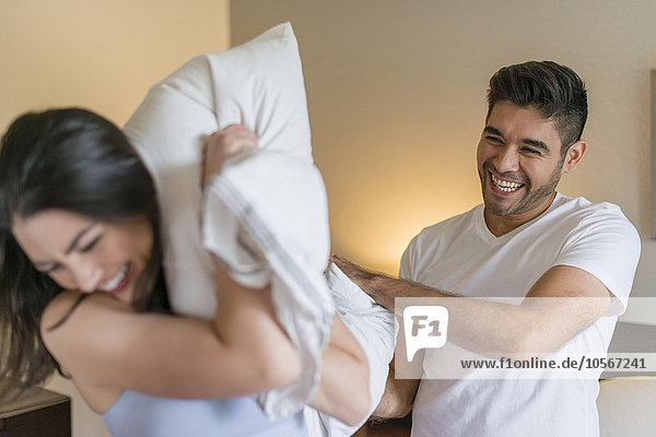 Hispanic couple having pillow fight