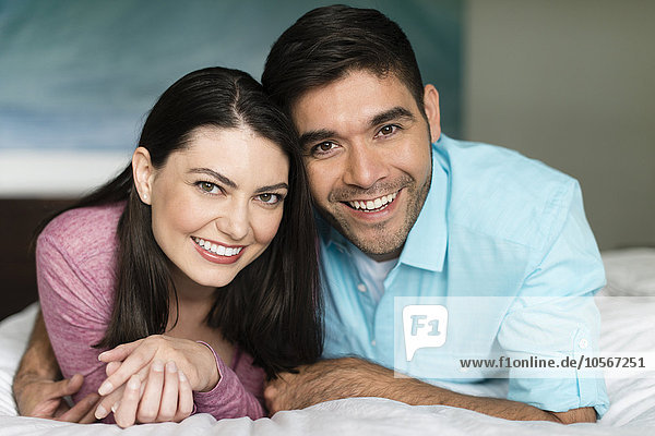 Hispanisches Paar lächelnd auf dem Bett