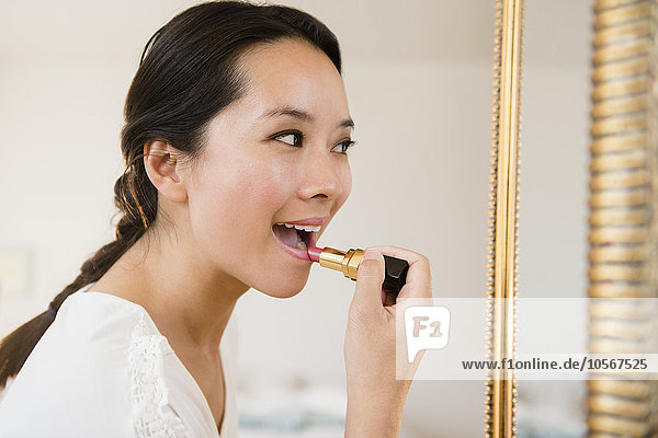 Chinese woman applying lipstick