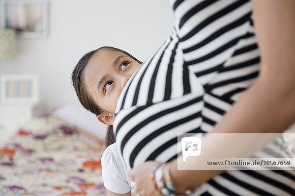 Mädchen bewundert Bauch der schwangeren Mutter
