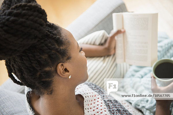 Black woman reading book and drinking coffee