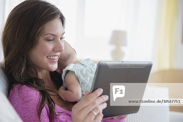 Mutter benutzt digitales Tablet und hält ihre kleine Tochter
