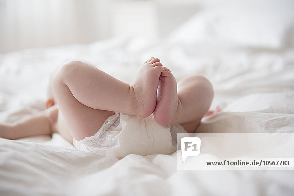 Legs of Caucasian baby girl laying on bed
