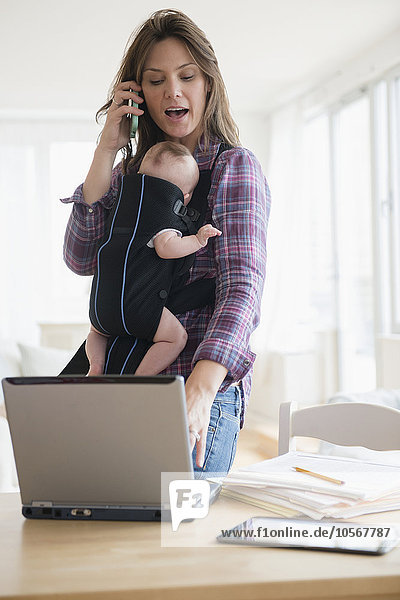 Mother working at home with new baby daughter