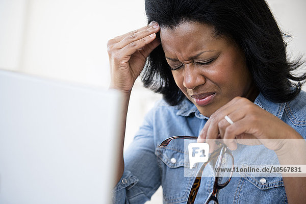 Frustrierte schwarze Frau reibt sich die Stirn