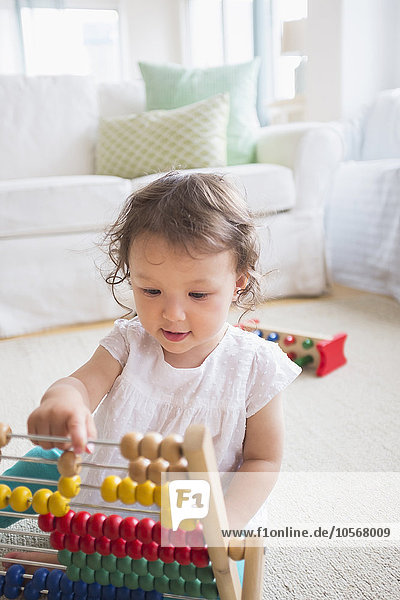 Mixed race baby girl playing with abacus