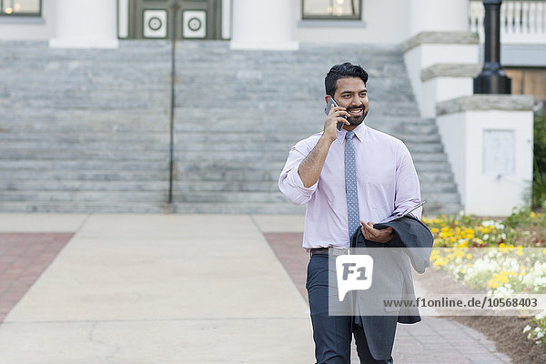 Indian businessman talking on cell phone on sidewalk