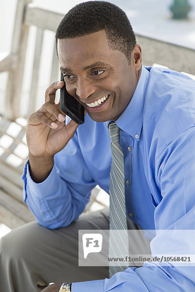 Schwarzer Geschäftsmann telefoniert mit Handy