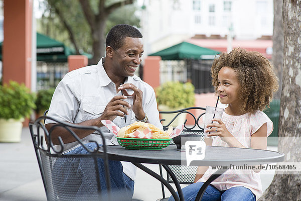 Father and daughter eating at outdoor restaurant table