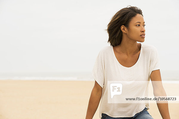 Nachdenkliche afroamerikanische Frau sitzt am Strand