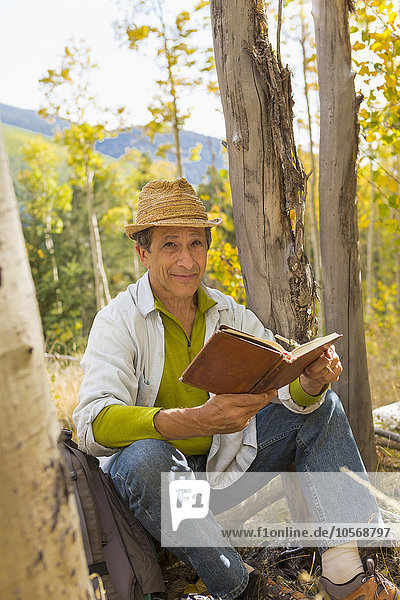 Mann liest Buch im Herbstwald