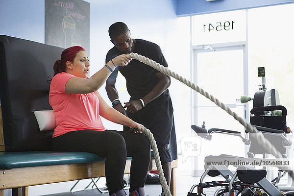 Behinderte Frau bei Physiotherapie mit Trainer