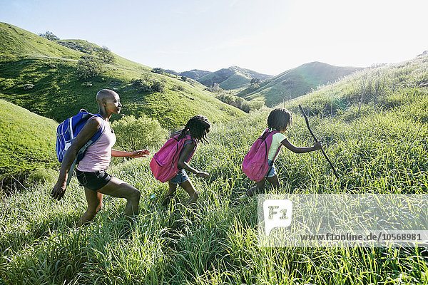 Black mother and daughters walking on rural hillside