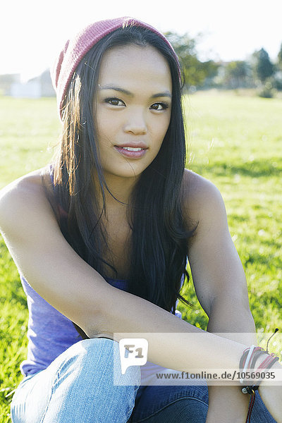 Asian woman sitting in grass