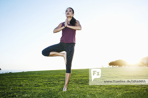 Asian woman practicing yoga outdoors