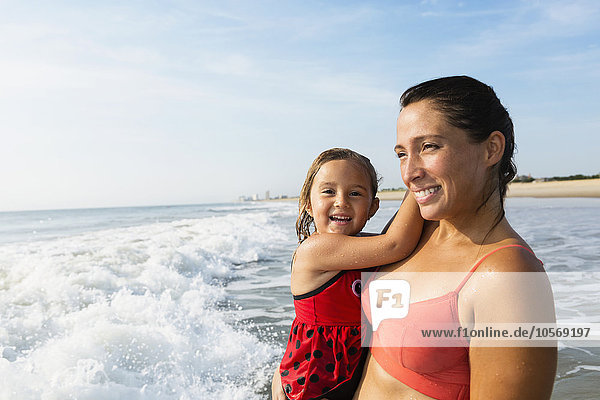 Mutter hält Tochter am Strand