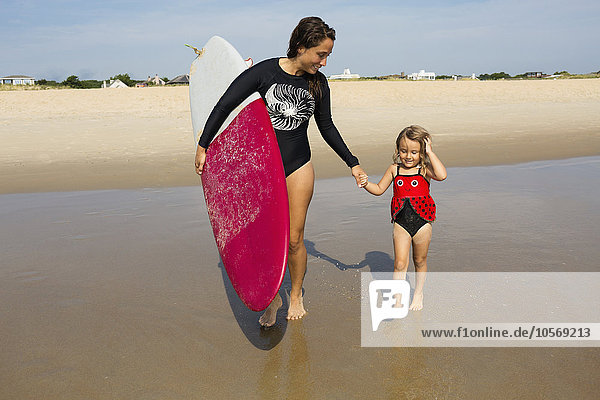 Mutter bringt Tochter das Surfen im Meer bei