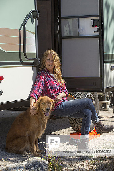 Caucasian woman petting dog at trailer