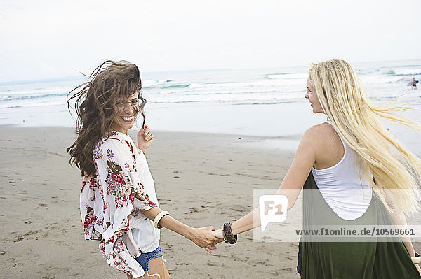 Caucasian women holding hands on beach
