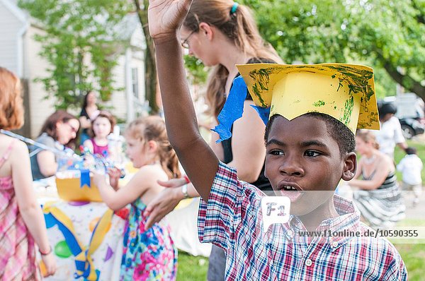 Portrait of young boy at kindergarten graduation  wearing paper mortar board