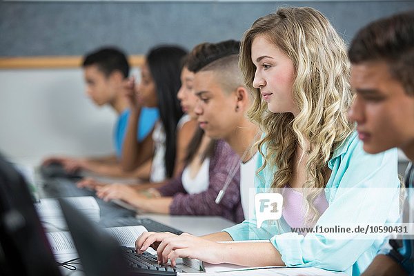 Row of teenage high school students typing on computers
