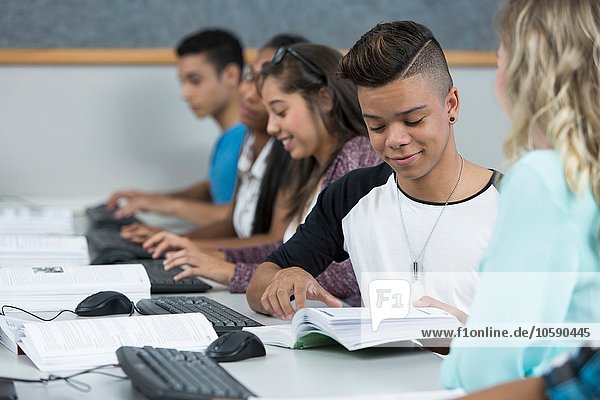 Row of teenage high school students working together in computer class