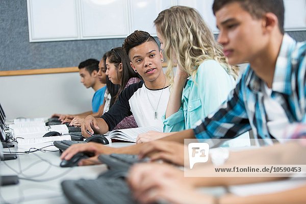 Row of high school students concentrating in computer class