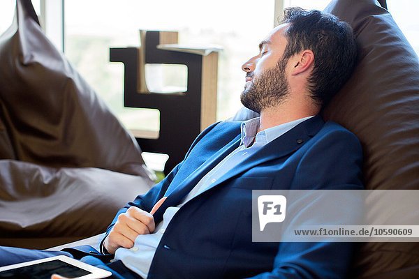 Jungdesigner schläft auf Sitzsackstühlen im Büro