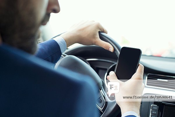 Jungunternehmer liest Smartphone-Text im Auto