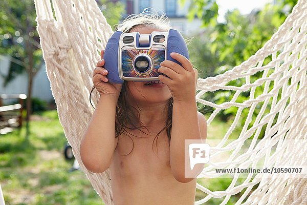 Mädchen hält Kamera über Gesicht im Garten
