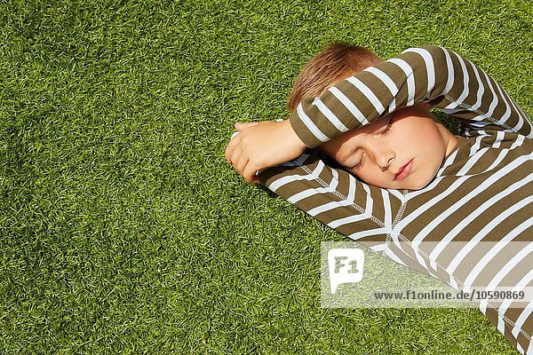 Hochwinkelansicht des auf Gras liegenden Jungen mit geschlossenen Augen