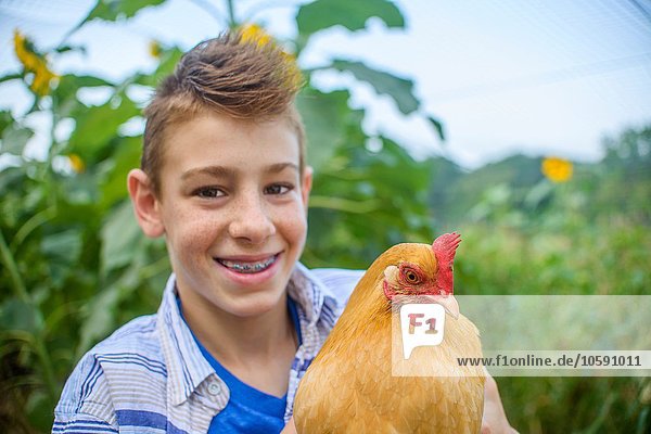 Portrait of boy in field holding hen