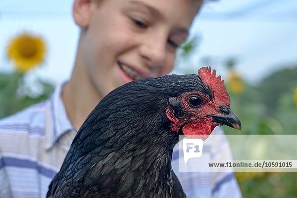 Close up portrait of boy in field holding hen