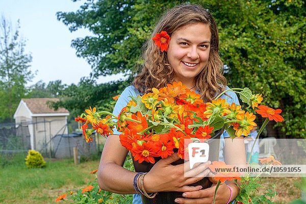Portrait of female farm worker holding a bucket of fresh cut flowers