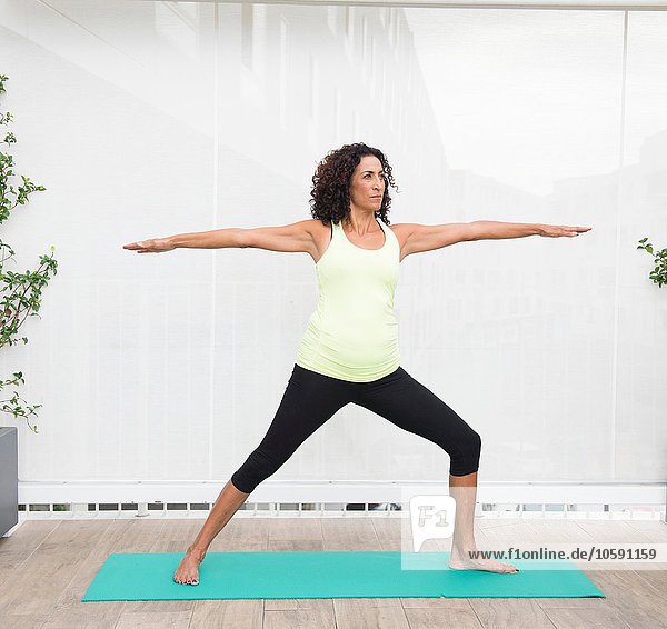 Reife Frau beim Yoga-Krieger posieren