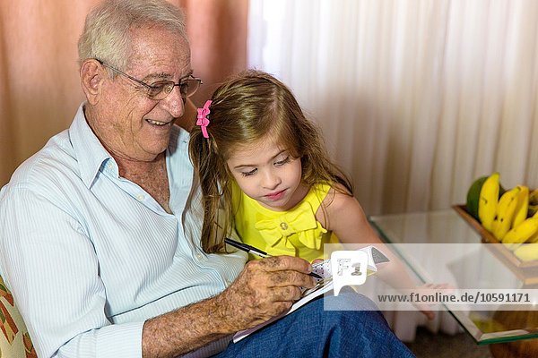 Mädchen sucht Großvater beim Schreiben im Notizbuch