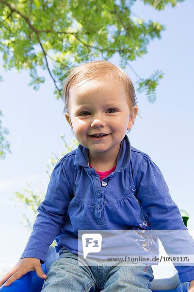 Portrait of female toddler sitting on top of garden slide