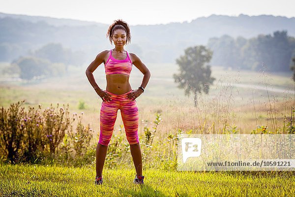 Portrait of confident young female runner in rural park
