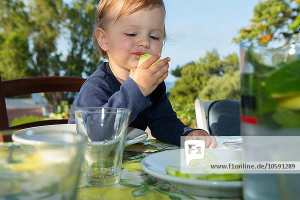 Weibliches Kleinkind beim Essen am Tisch im Freien
