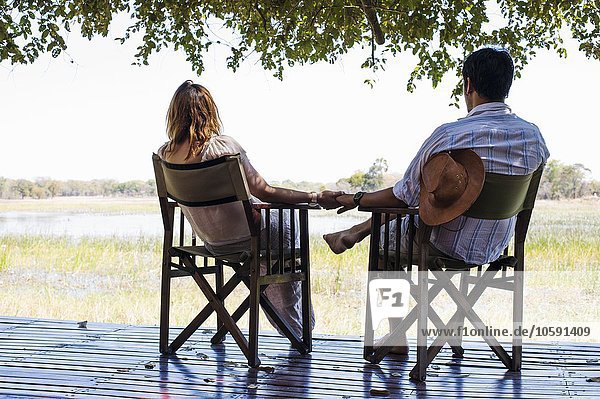 Romantic couple holding hands whilst sitting at safari lodge  Kafue National Park  Zambia