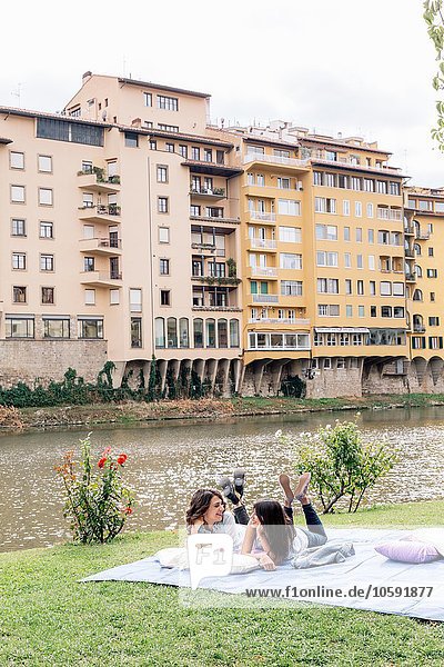 Lesbian couple lying on front on blanket next to Arno river  Florence  Tuscany  Italy