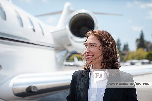 Mid adult female businesswoman and private jet at airport